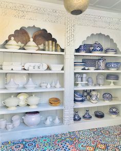 a room filled with lots of white and blue dishes on top of bookshelves