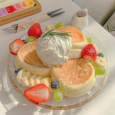 a plate topped with pancakes covered in whipped cream and fruit