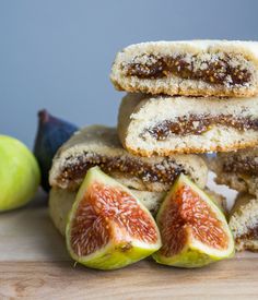 three pieces of bread are stacked on top of one another with figs and an apple in the background