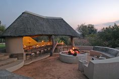 an outdoor dining area with fire pit, seating and table set up for two at dusk