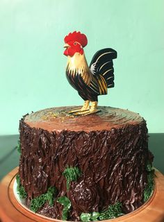 a cake decorated with chocolate icing and a rooster figurine sitting on top of it