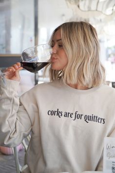 a woman sitting at a table with a glass of wine in her hand and the words cooks are for quitters printed on it