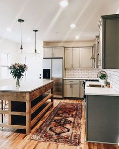 a kitchen with an island, sink and stove top oven next to a refrigerator freezer