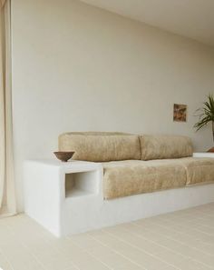 a white couch sitting in the middle of a living room next to a potted plant