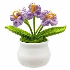 crocheted flowers in a white vase with green leaves