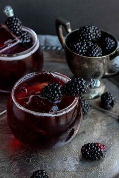 two glasses filled with blackberries on top of a silver tray