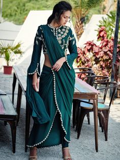 A beautiful lightweight and lavish drape set for a beach wedding or a dinner party. The top is a beautiful amalgamation of geometric and floral motifs; adorned with pearl and sequin details. The sleeve has a smart cuff opening overlapping at the hem with embroidery. The blouse has a back opening. The cigarette pants are composed in tussar silk overlapped with a skirt drape. The drape has beautiful hand embroidery at the hem. A second drape is attached at the waist, becoming a pallu. The pleating Pant Saree, Blue Anarkali, Green Drapes, Fusion Wear, Skirt Draping, Drape Pants, Tulip Sleeve, Green Saree, Embellished Blouse