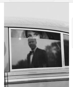 a black and white photo of a woman in a car looking out the window