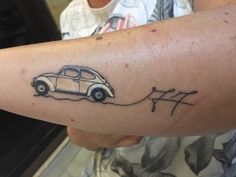 a person with a tattoo on their arm that has a small car attached to it