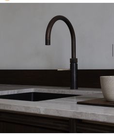 a kitchen sink with a black faucet and white bowl on the countertop