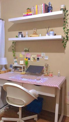 a desk with a laptop on top of it and shelves above the desk behind it