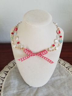 a white mannequin with a red ribbon on it's neck and beads