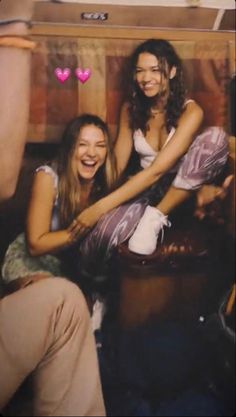 two young women sitting next to each other in front of a wooden box with hearts on it