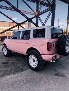 a pink pick up truck parked under a bridge