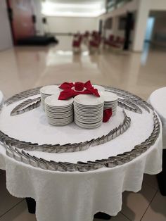 a white table topped with plates covered in red ribbon and bows on top of it