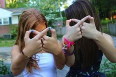 two girls making the v sign with their hands