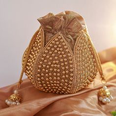 Discover the Elegant Lotus Potli Bag by THE TAN CLAN Elevate Your Style with Our Unique Embroidered Indian Bridal Potli Bag by THE TAN CLAN Transform your accessory collection with the Elegant Lotus Potli Bag--a stunning fusion of traditional craftsmanship and modern design. This exquisite embroidered potli bag is perfect for weddings, engagements, bridesmaid gifts and anniversary gifts. With its intricate detailing and luxurious finish, this bag is a must-have for anyone looking to add a touch Gold Openable Potli Bag For Wedding, Gold Embellished Bollywood Style Bags, Bollywood Style Embellished Bags For Wedding, Bollywood Style Embellished Gold Bags, Bollywood Style Embellished Wedding Bag, Gold Bridal Accessories For Reception And Festivals, Traditional Embellished Gold Potli Bag, Traditional Gold Embellished Potli Bag, Embellished Gold Potli Bag For Wedding