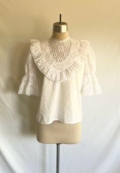 Beautiful 1980's Victorian style lace puff sleeve blouse featuring a semi sheer yoke, lace trimmed crew neck and ruffles! Solid part of blouse is a white cotton blend. The rest of the blouse is a floral nylon lace.  Blouse zips up the back with a plastic zipper. Blouse is clean and in excellent condition!  Label:  Kate Schorer - Colorado Springs, CO - Made in USA - S Measurements: would best fit a modern size S/M Bust= 38 1/2" Bottom opening= 42" Shoulder width= 13 1/2" Sleeve length= 13" Bicep= 18" Sleeve opening= 8" relaxed, stretches to 14" Body length from side neck down to hem edge= 23" White Victorian Blouse, Summer Lace Blouse With Puff Sleeves, Short Sleeve Lace Top With Ruffles, Bohemian Broderie Anglaise Lace Top For Summer, Summer Puff Sleeve Lace Top, Summer Lace Top With Puff Sleeves, Lace Puff Sleeve Top With Lace Collar, Cottagecore Blouse With Lace Collar, Bohemian Lace Top With Lace Collar For Spring