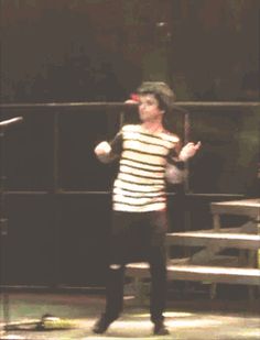 a man standing in front of a microphone on top of a wooden floor next to a bench