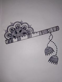 a pen and some beads on a white sheet with an intricate design hanging from it