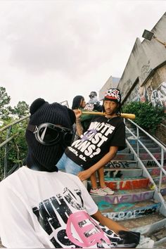 a group of young men standing next to each other in front of stairs with graffiti on them