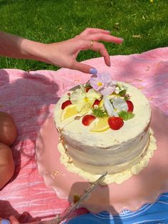 a person is cutting into a cake with strawberries and lemons on the table