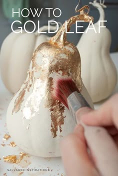 someone is painting gold leaf on a white pumpkin