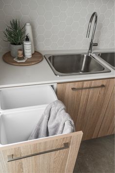 a kitchen sink with an open trash can in the middle and a wooden cabinet underneath it