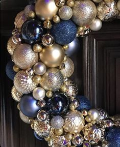 a wreath made out of ornaments hanging from the front door with blue and gold balls on it