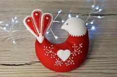 a red and white bird ornament sitting on top of a wooden table next to string lights