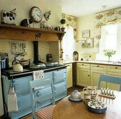 an old fashioned kitchen with blue cabinets and wooden table in front of the stove top