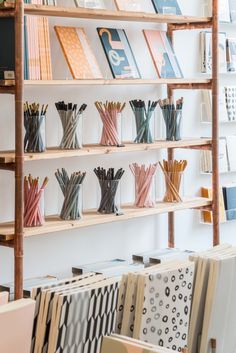 the shelves are filled with many different types of papers and pencils in vases