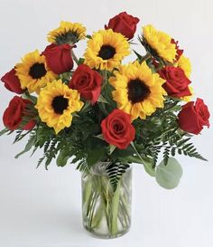 a vase filled with red roses and yellow sunflowers