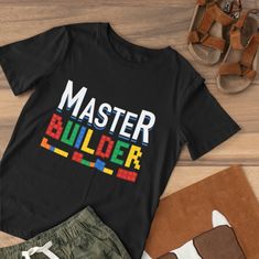 a black t - shirt with the words master builder on it next to some sandals