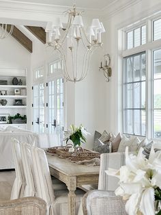 a living room filled with furniture and a chandelier hanging from the ceiling over a table