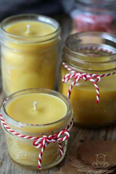 three jars filled with candles sitting on top of a wooden table