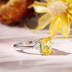 Always be on her mind when you propose with this classic three stone emerald-cut engagement ring. It is a classic piece with a lower profile that features emerald-cut yellow stone with a pair of trillion-cut white stone to bring the sparkle up. This classic designed ring will really look amazing on your bride-to-be's finger and it will be a gift that she never forgets.Carat Weight: 3.65 ctStone Size: 7*9 mmStone Type: Jeulia® StoneNumber of Stones: 1 Stone Shape: RadiantStone Color: Citrine YellowCarat Weight: 0.69 ctStone Size: 4*4 mmStone Type: Jeulia® StoneNumber of Stones: 2 Stone Shape: TrillionStone Color: Diamond WhiteWeight: 3.52 gMaterial: 925 SilverPlating Color: Silver, Yellow Gold Elegant Yellow Emerald-cut Diamond Ring, Elegant Yellow Emerald Cut Diamond Ring, Gift Emerald Ring With Three Stones In Radiant Cut, Yellow Emerald-cut Diamond Wedding Ring, Three Stone Radiant Cut Jewelry, Yellow Emerald Cut Diamond Ring, Yellow Emerald-cut Diamond Ring With Prong Setting, Classic Yellow Diamond Ring Baguette Cut, Formal Three Stone Yellow Jewelry