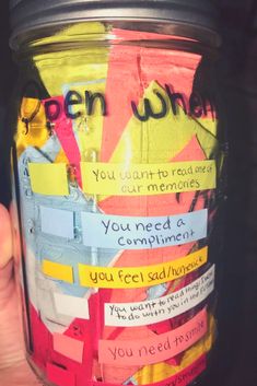 a person holding up a jar with writing on it and paper taped to the side