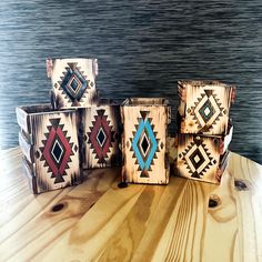 four wooden boxes with designs on them sitting on a wood table next to the water