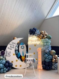 a rocket ship balloon arch with stars and moon on the top, surrounded by balloons