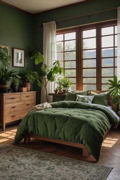 a bed with green comforter and pillows in a room next to two large windows