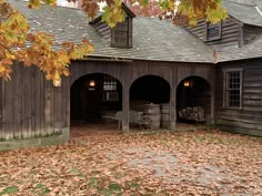 an old wooden building with lots of leaves on the ground