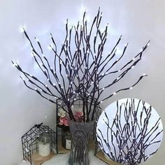 a vase filled with branches next to a mirror on a counter top covered in lights