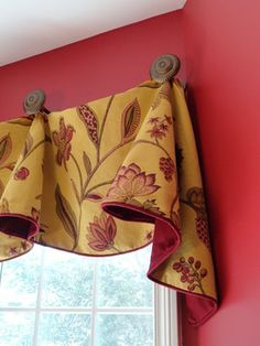 a window with a yellow and red flowered valance hanging from it's side