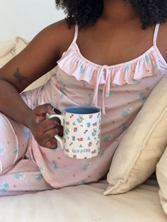 a woman sitting on a bed holding a coffee mug