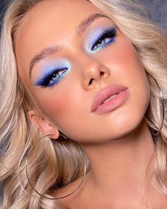 a woman with bright blue makeup and hoop earrings