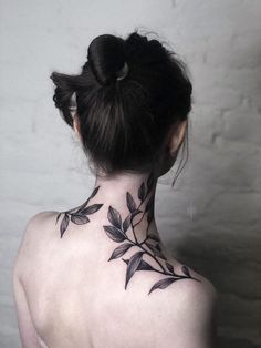 the back of a woman's neck with black leaves on her upper and lower part