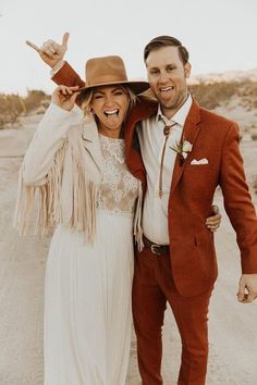 a man and woman are posing for the camera in front of a dirt road with their arms around each other