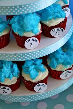 cupcakes with blue frosting are stacked on three tiered trays that say thing 2, thing 3 and thing 4