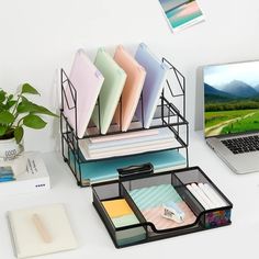 a laptop computer sitting on top of a desk next to a stack of folders